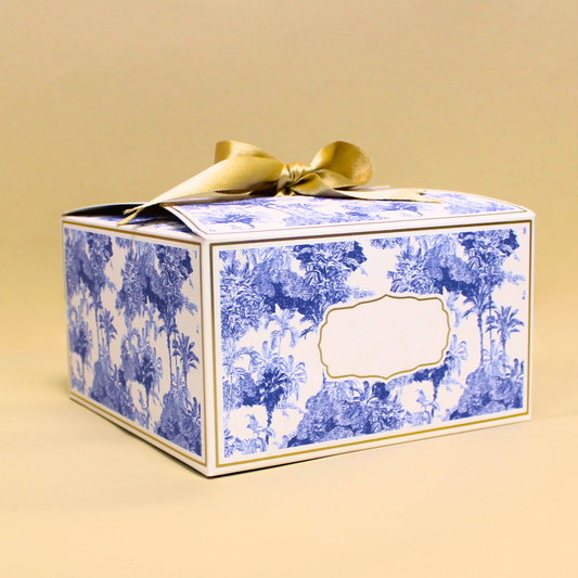 Decorative gift box with blue floral pattern and gold ribbon on a beige background